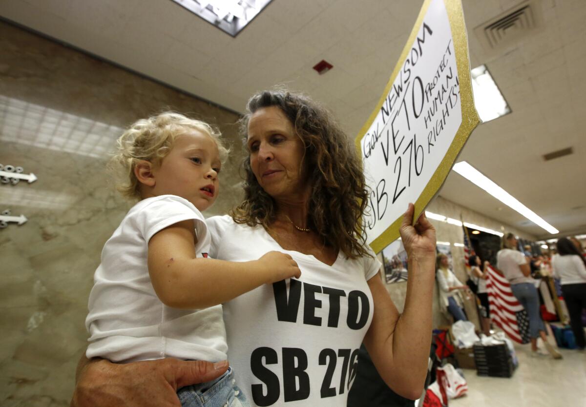Vaccination protester Kim Whitley holds her granddaughter Kole