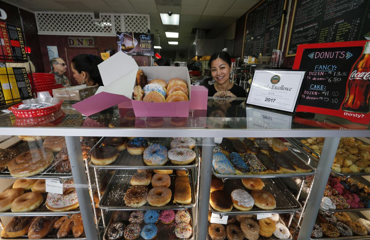 Susan Lim, propietaria estadounidense camboyana de Rose Donuts & Cafe, sirve donuts en su tienda de San Clemente (Allen J. Schaben / Los Angeles Times).