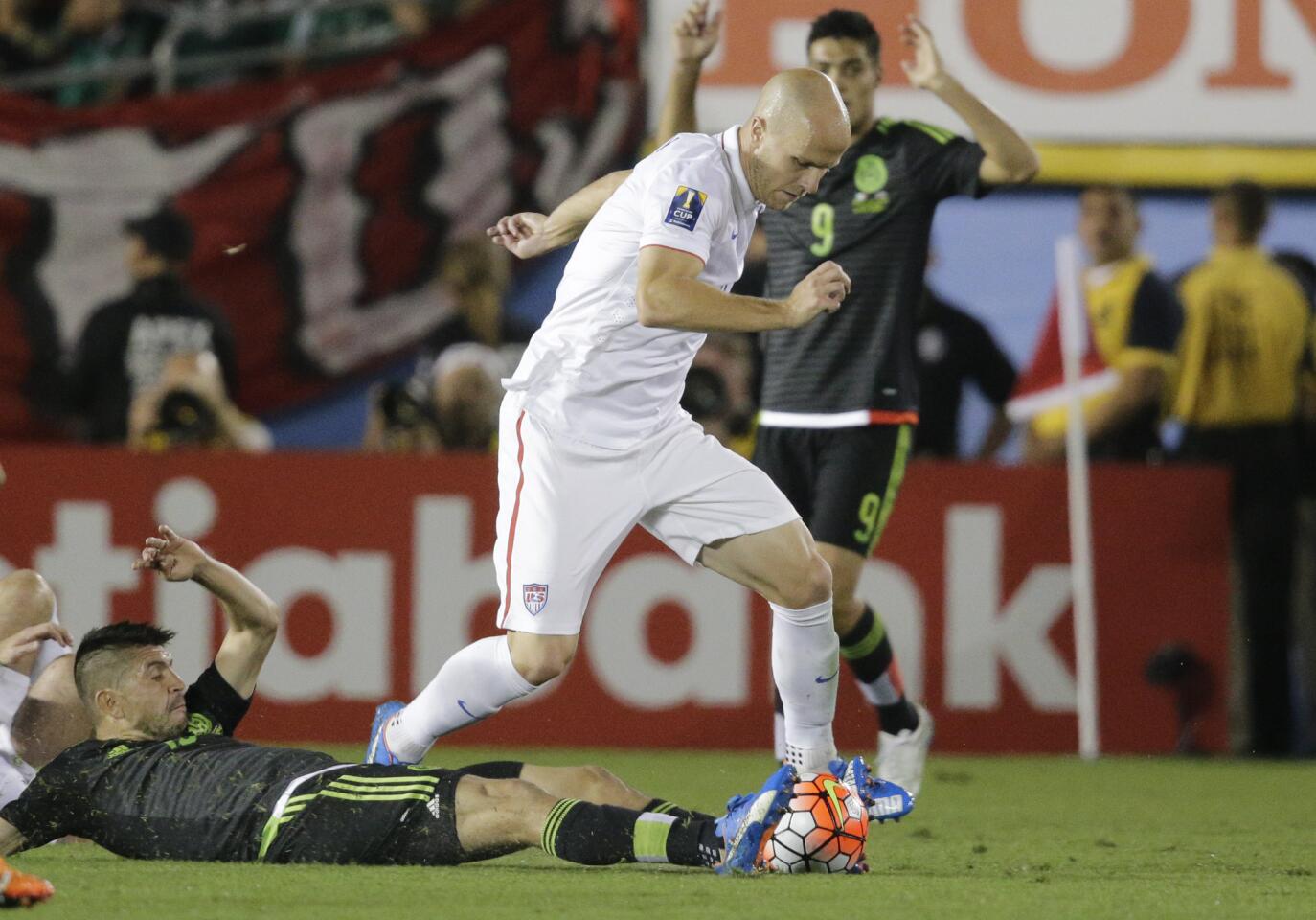 Mexico's Oribe Peralta, on the ground, attempts to take the ball from United States' Michael Bradley during the CONCACAF Cup soccer match at the Rose Bowl Stadium, in Pasadena , Calif. Saturday, Oct. 10, 2015, (AP Photo/Jae C. Hong)
