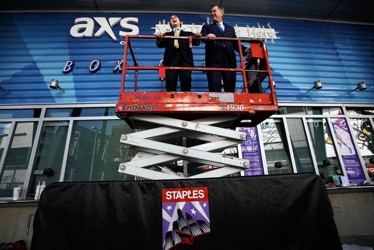 AEG executives Bryan Perez, left, and Tim Leiweke ride a scissors jack outside the ticket office at Staples Center on Feb. 1, 2013, as workers were putting the finishing touches on its new look.