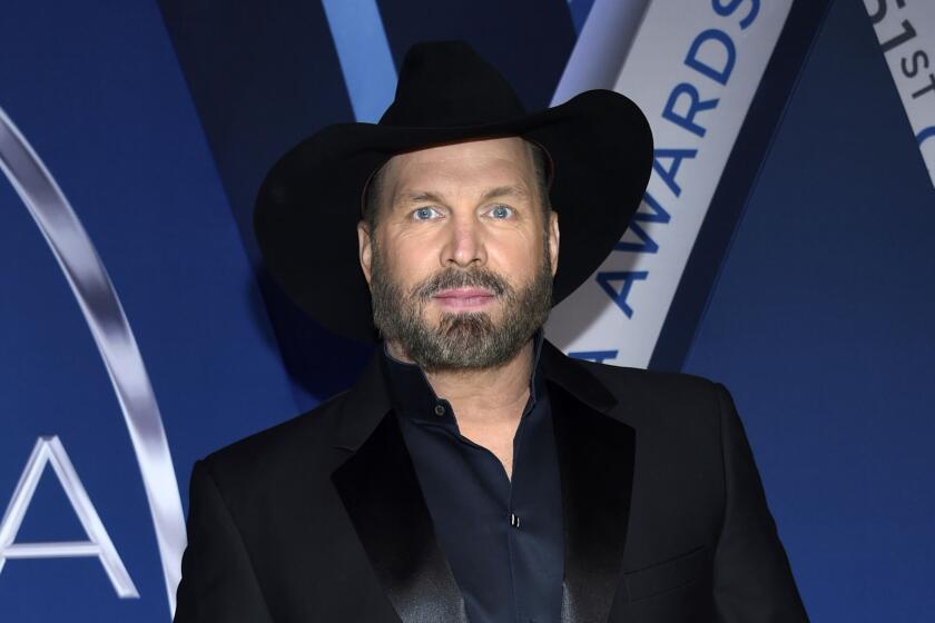 Grath Brooks wears a black cowboy hat, shirt and suit