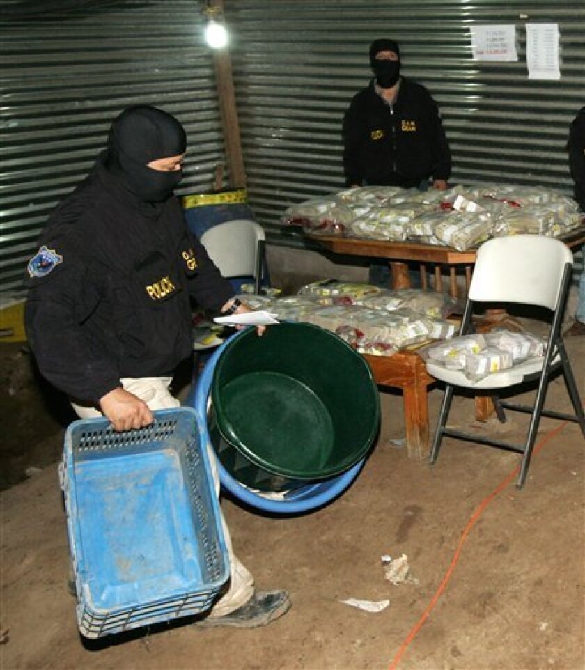 A police officer shows to journalists the containers in which over 9 million US dollars, displayed at back, were found buried in a rural area in Zacatecoluca state, east of San Salvador, El Salvador, Friday, Sept. 3, 2010. According to government investigator Jorge Cortez, the money is related to drug trafficking. (AP Photo/Rony Gonzalez, La Prensa Grafica) EL SALVADOR OUT – NO USAR EN EL SALVADOR