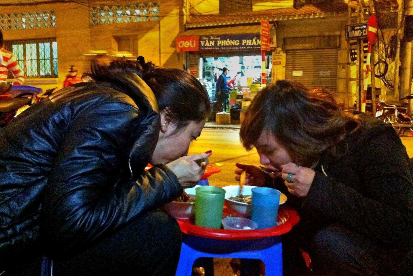 Friends enjoy chicken soup made with noodles and served with liver chunks at a street stall in Hanoi's Old Quarter.