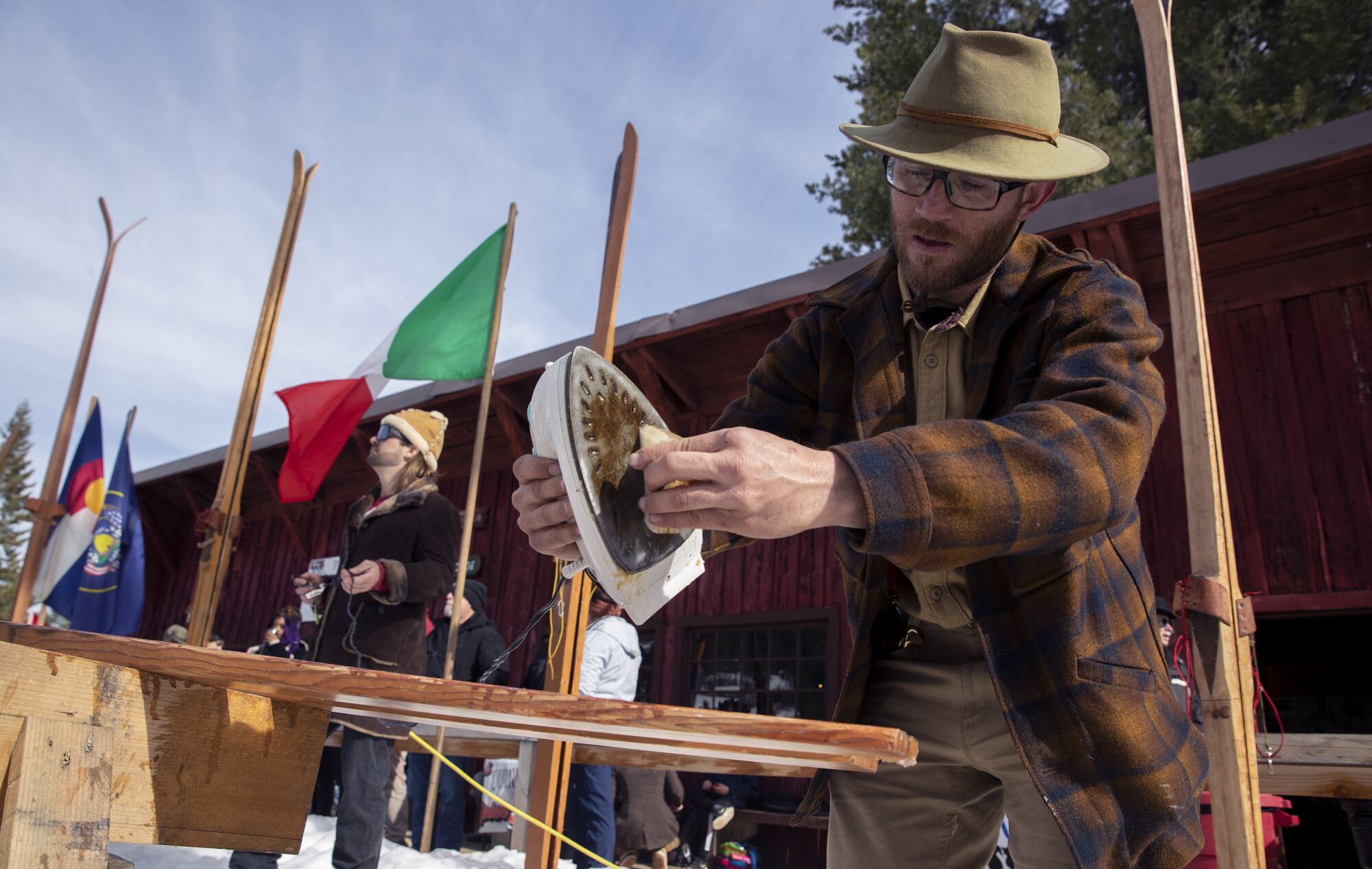A man uses an iron to melt wax onto his skis