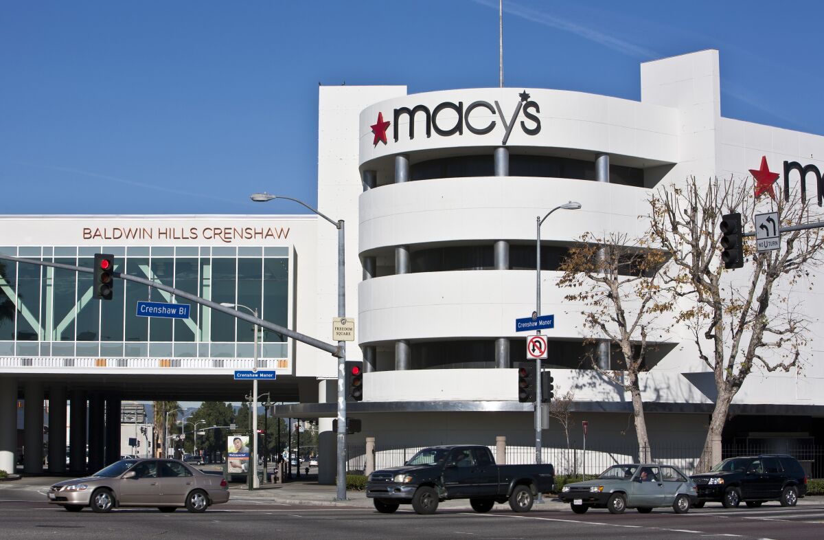 Cars driving on a street in front of a Macy's