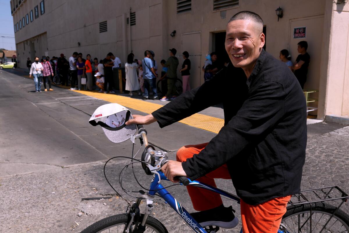 A man smiles while sitting on a bike and looking at the camera.