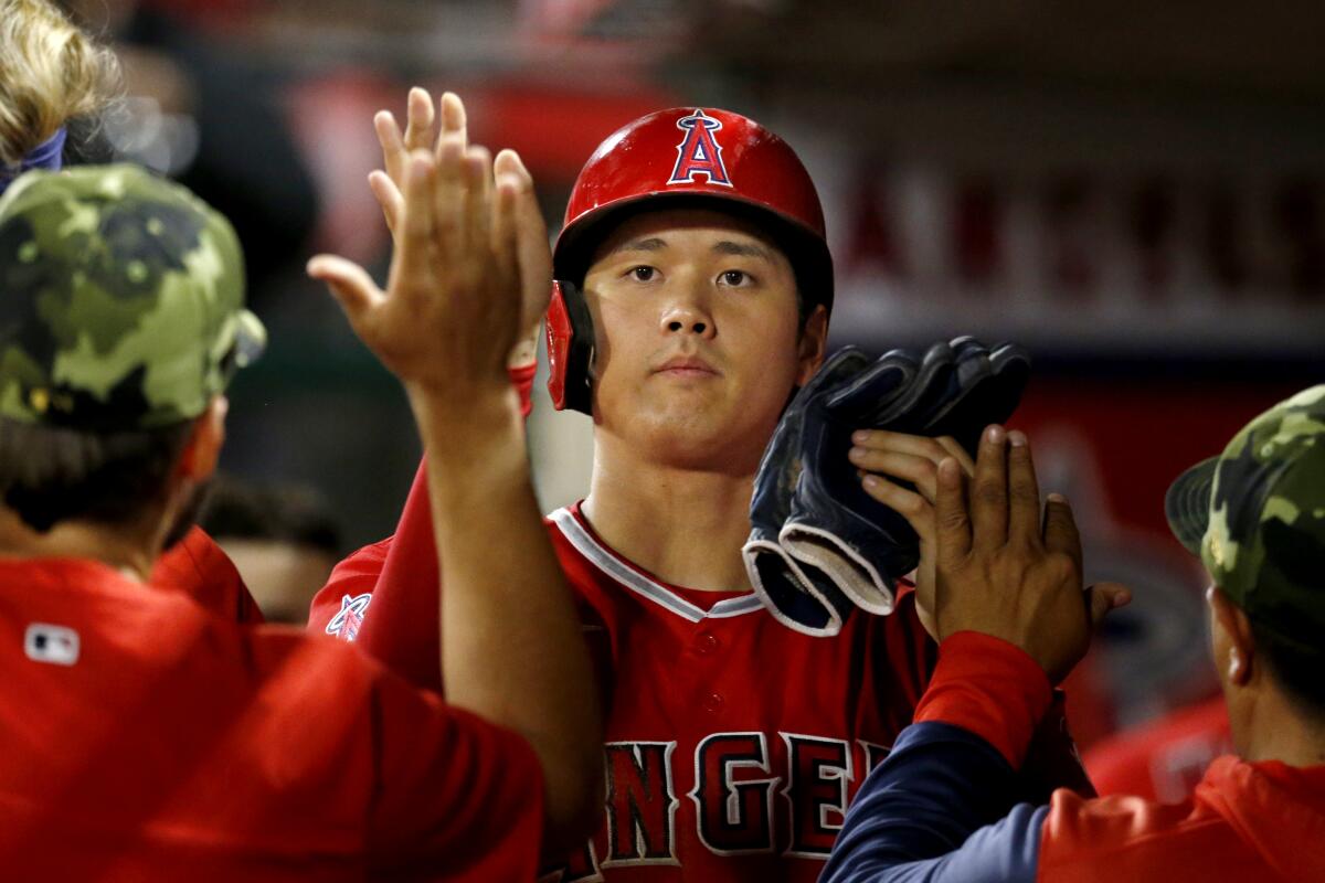 Angels designated hitter Shohei Ohtani is congratulated by teammates after scoring on a walk on May 21, 2022.