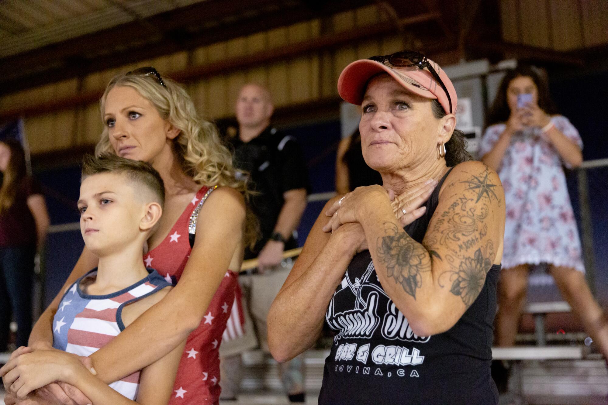 Two women and a boy stand and listen.