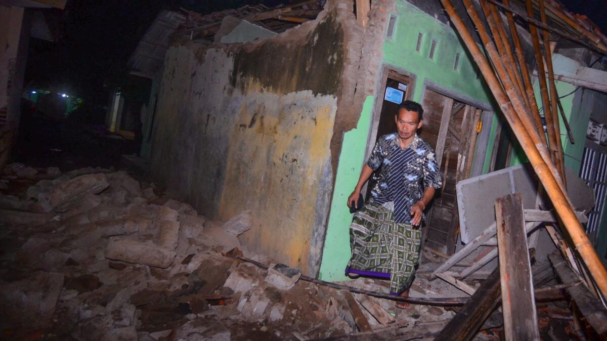 An Indonesian man steps out of a damaged house as he checks on his belongings after the earthquake hit West Java.