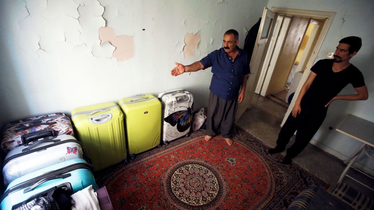 Seid Moradi, left, with son Sirvan, shows his family's suitcases that they have packed for their scheduled flights to the United States.
