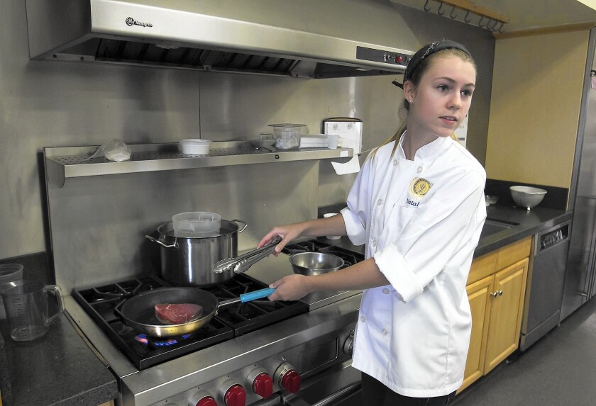 Student chef and team leader Natalia Tortorello cooks seared ahi in her Newport Harbor culinary class on Friday.
