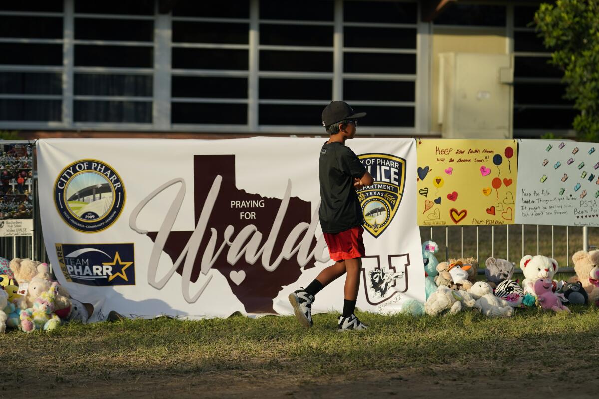  un niño camina junto a un memorial en las afueras de la Escuela Primaria Robb, en Uvalde, Texas,