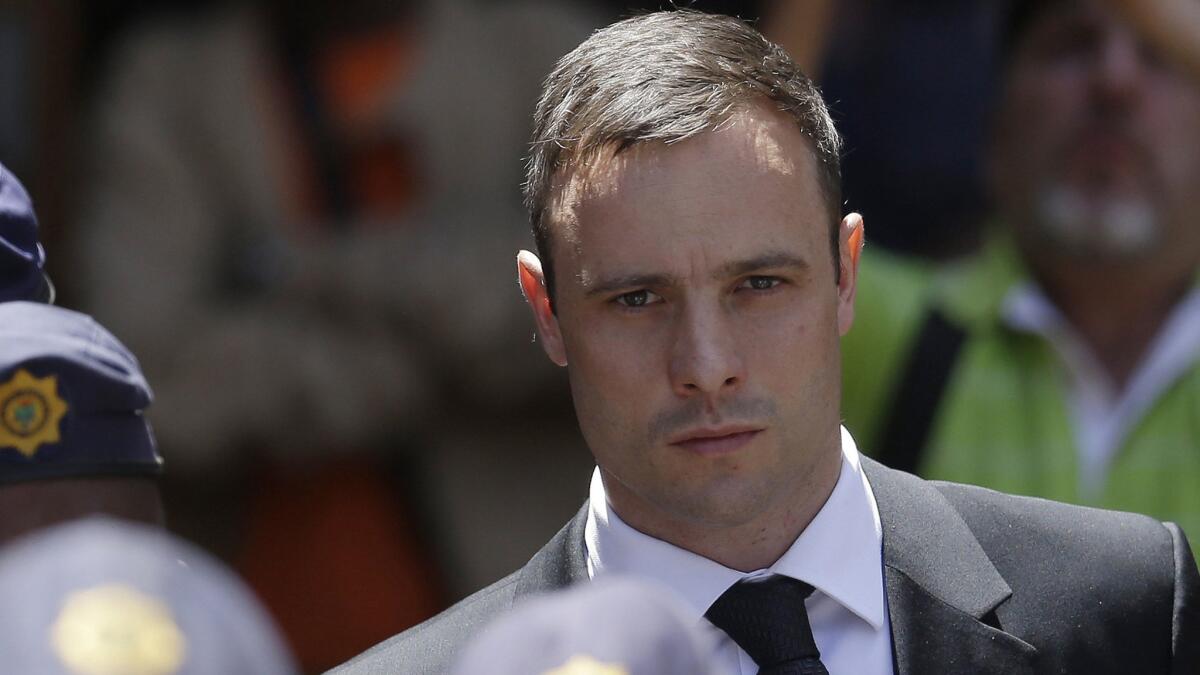 Former Olympic runner Oscar Pistorius is escorted by police officers after leaving a courthouse in Pretoria, South Africa, on Oct. 17, 2014.