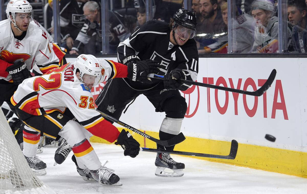 Anze Kopitar passes the puck under pressure from Calgary's Paul Byron on Monday during the Kings' last game before Christmas break.