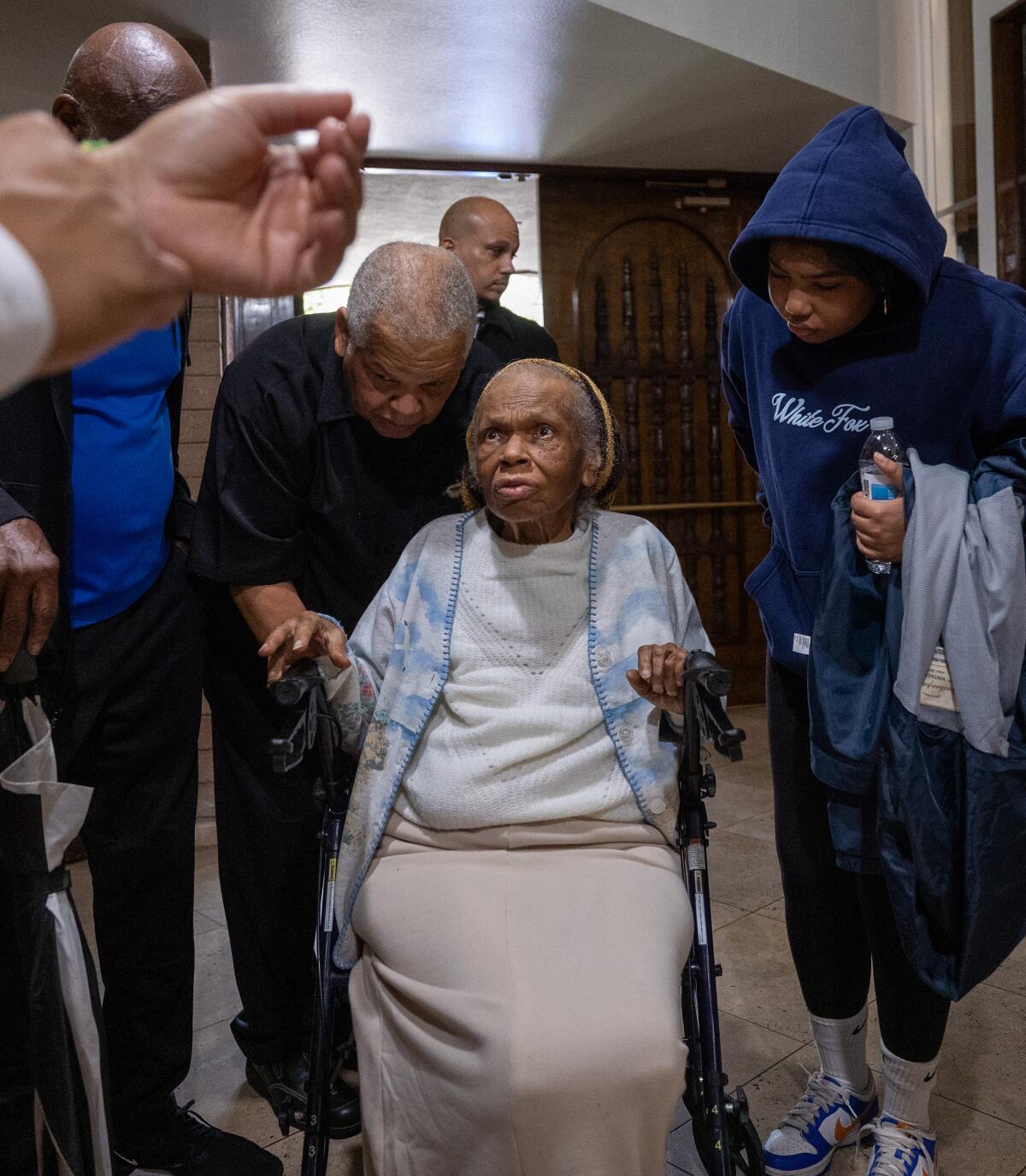 A woman using a wheelchair is aided at a memorial service at First AME Church in Pasadena.
