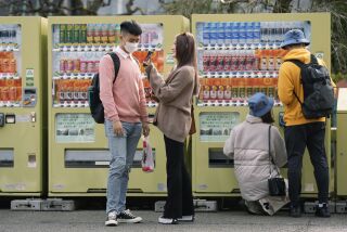 Turistas de Taiwán miran sus fotos frente a máquinas expendedoras mientras visitan el templo budista Sensoji en Tokio, el viernes 13 de enero de 2023. (Foto AP/Hiro Komae)
