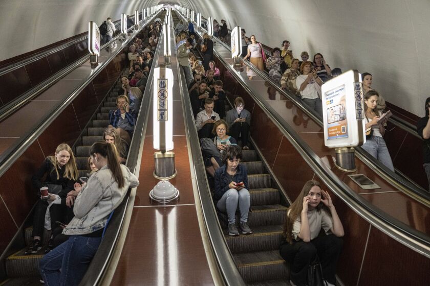 Decenas de personas aguardan en las escaleras eléctricas de una estación del metro usada como refugio durante un ataque con cohetes rusos en Kiev, Ucrania, el lunes 29 de mayo de 2023. (AP Foto/Evgeniy Maloletka)