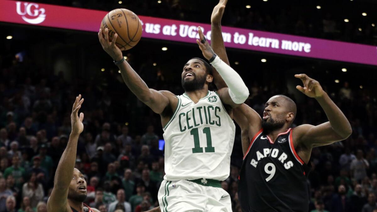 Boston Celtics guard Kyrie Irving (11) splits the defense of Toronto Raptors forwards Kawhi Leonard (2) and Serge Ibaka (9) on the way to the hoop during overtime.