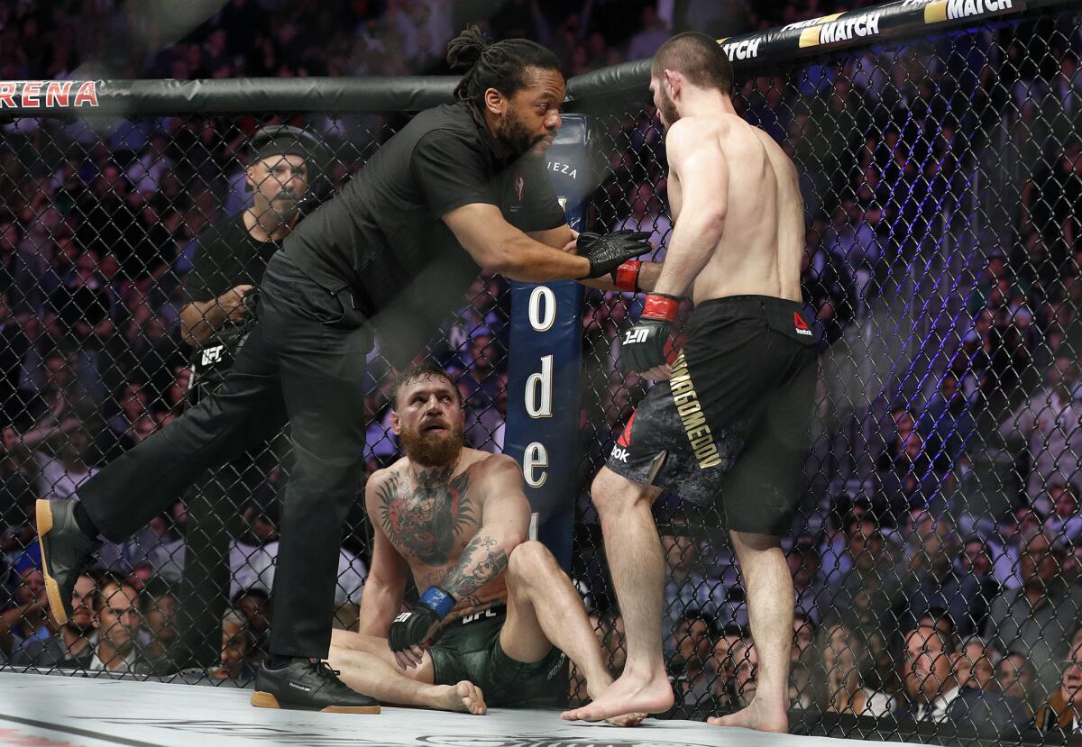 Khabib Nurmagomedov, right, is held back by referee Herb Dean after fighting Conor McGregor, bottom, during a lightweight title mixed martial arts bout at UFC 229 in Las Vegas, Saturday, Oct. 6, 2018. Nurmagomedov won the fight by submission during the fourth round to retain the title.