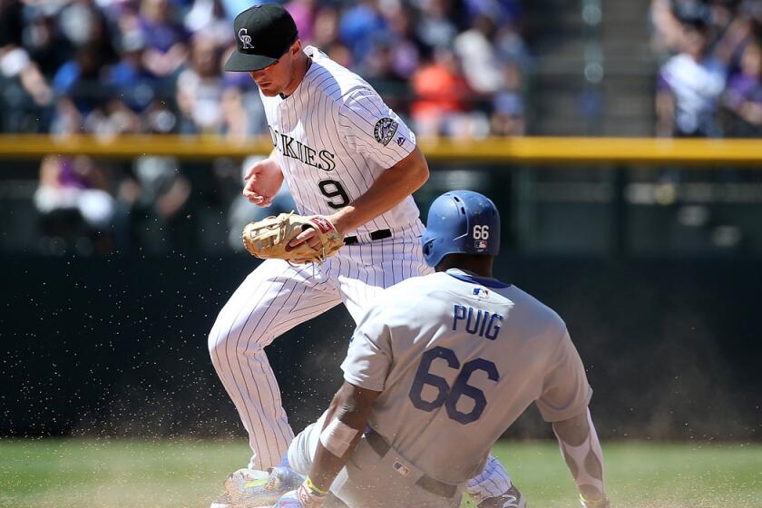 Dodgers' Yasiel Puig slides into second as Colorado Rockies second baseman DJ LeMahieu takes the late throw in the second inning on Sunday.