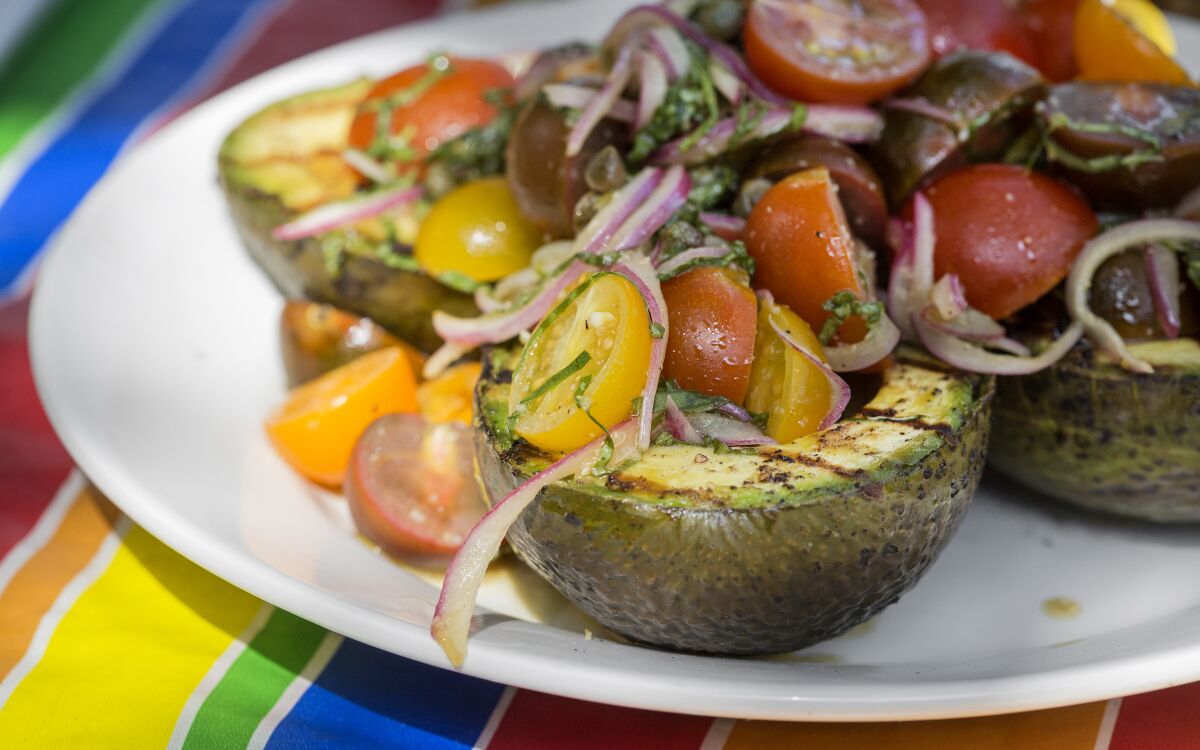 Grilled avocado halves topped with marinated tomato salad 
