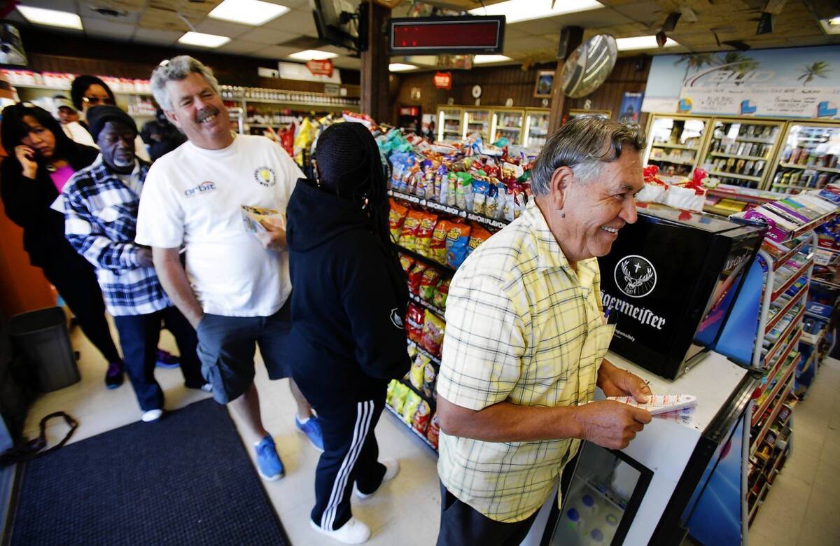Rafael Moreno picks Powerball numbers Monday as others form a line at Bluebird Liquor in Hawthorne. California is the latest state to participate in Powerball.