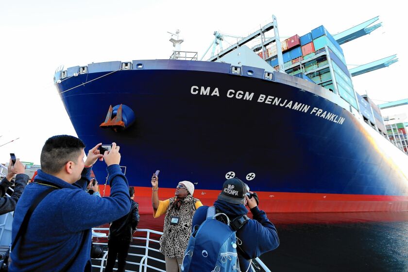 People aboard a passing boat take pictures of the CMA CGM Benjamin Franklin as it unloads cargo at the Port of Los Angeles. The Franklin is the largest container ship to visit a North American port.
