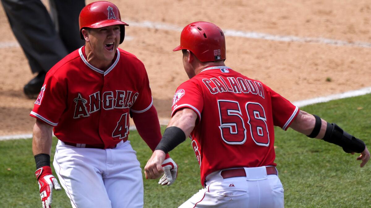 Angels right fielder Kole Calhoun (56) celebrates with teammate Daniel Robertson after scoring the winning run against the Mariners on a wild pitch in the 10th inning Sunday in Anaheim.