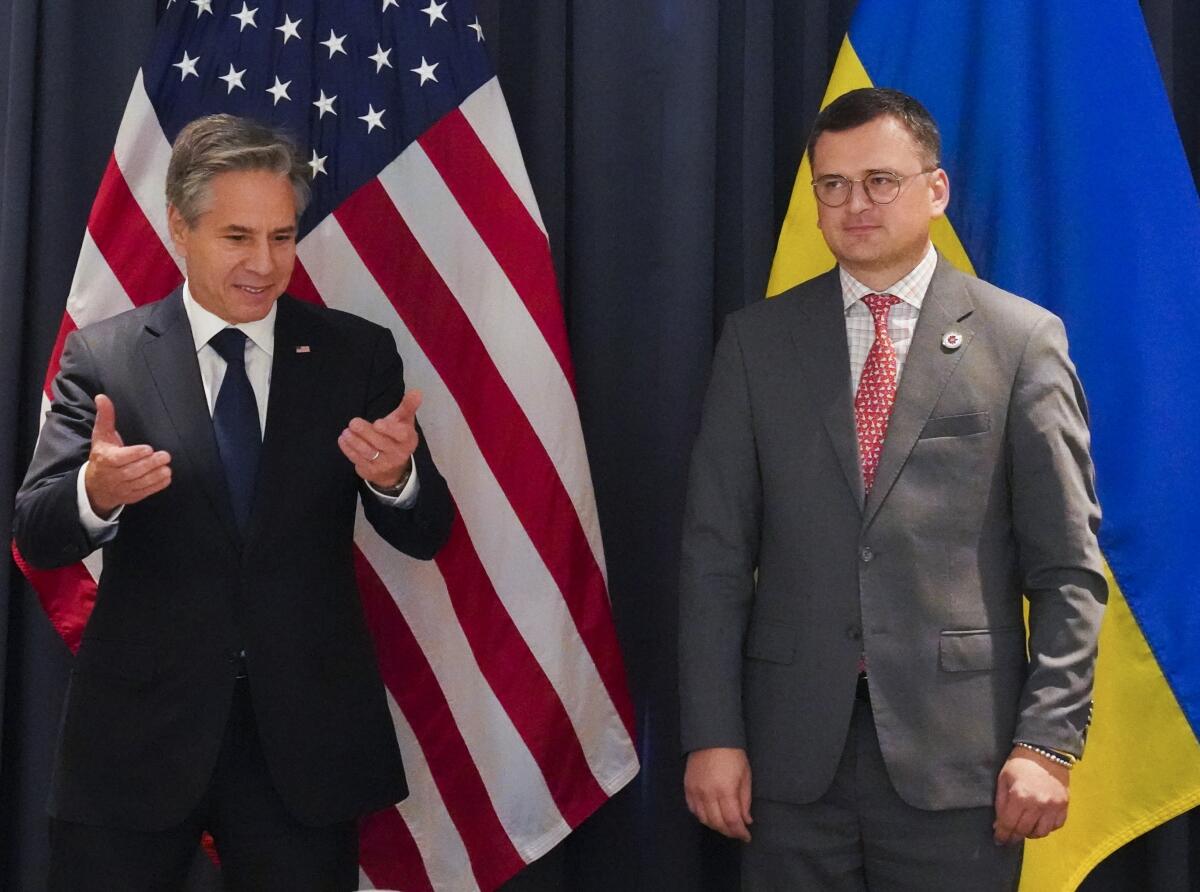 U.S. Secretary of State Antony J. Blinken stands next to Ukraine Foreign Minister Dmytro Kuleba in front of flags.