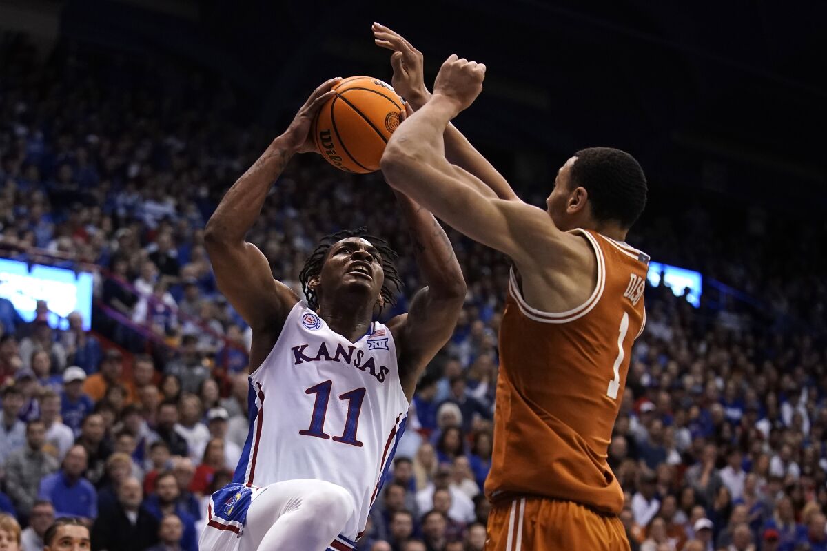 Kansas guard MJ Rice (11) shoots under pressure from Texas forward Dylan Disu (1) during the first half of an NCAA college basketball game Monday, Feb. 6, 2023, in Lawrence, Kan. (AP Photo/Charlie Riedel)