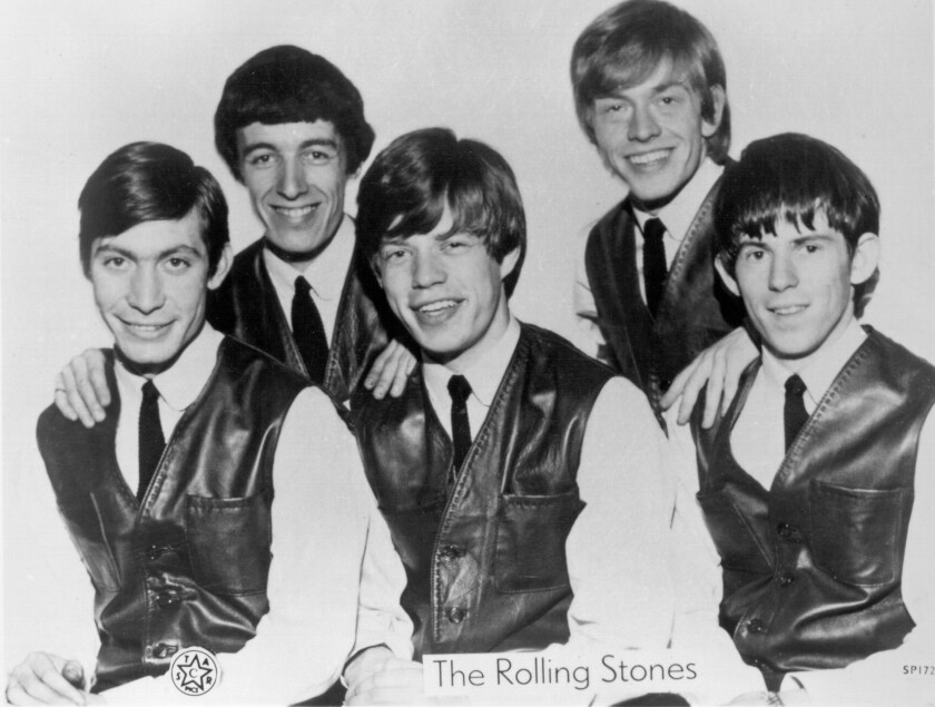 Five young men in shirts, ties and vests smile as they pose for a portrait.