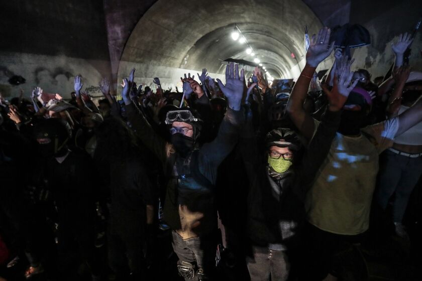 Los Angeles, CA, August 26, 2020 - Protesters raise their hands as LAPD officers converge on them from both sides in the Third St. underpass. (Robert Gauthier / Los Angeles Times)