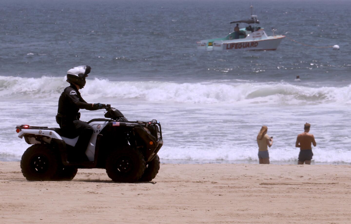 A police officer and a lifeguard boat comb the shoreline in Venice Beach on July 5.