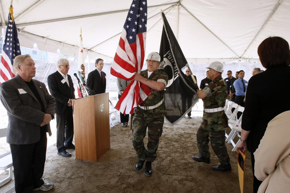 Glendale mayor Dave Weaver, left, stands at attention as the Color Guard presents the flag during the groundbreaking ceremony for Veteran's Village, the new 44-unit affordable rental housing project for low income U.S. veterans, on west Salem Street in Glendale on Wednesday, Feb. 19, 2014.