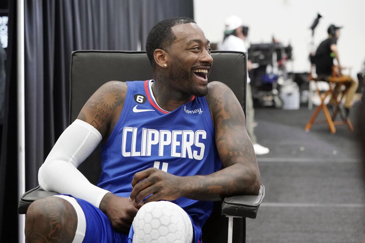 Clippers guard John Wall smiles while seated in a chair as he fields questions during media day.
