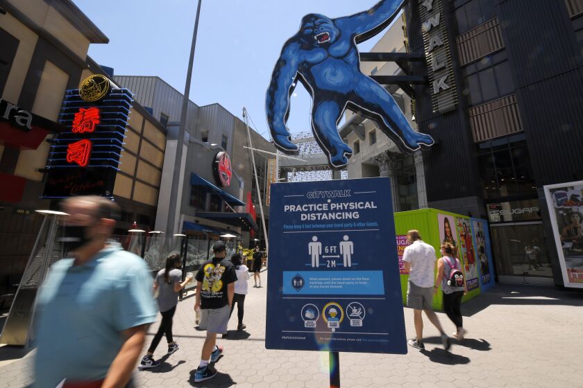 People walk through Universal CityWalk, Thursday, June 11, 2020, near Universal City, Calif. The tourist attraction, which had been closed due to the coronavirus outbreak recently re-opened. The Universal Studios tour is still closed. (AP Photo/Mark J. Terrill)