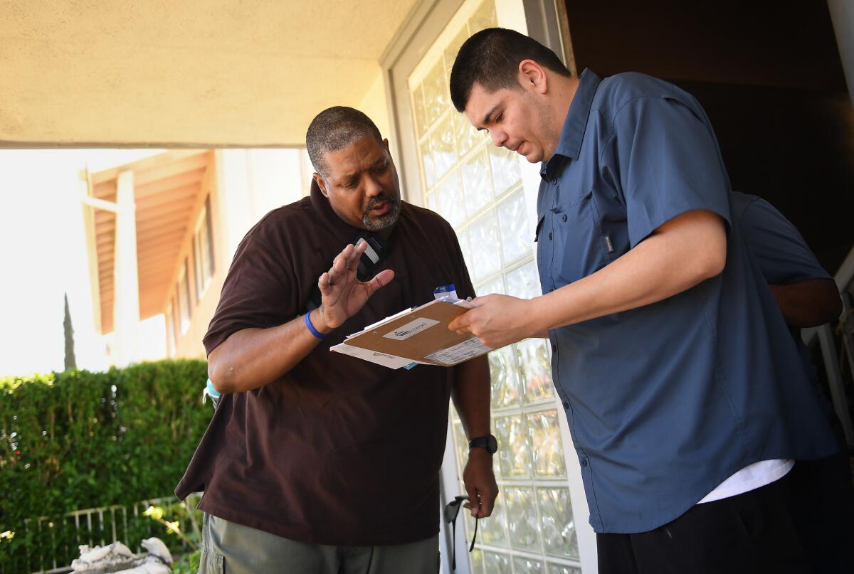 Derek Bryson, left, a volunteer from Los Angeles, helps Erick Guillen, 25, of Simi Valley sign up to vote by mail. Democrats covet the seat held by Rep. Steve Knight, a Palmdale Republican.