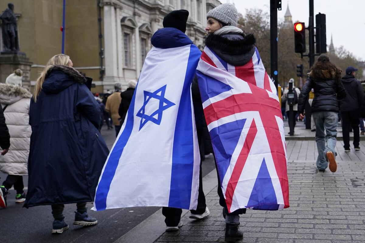 Dos manifestantes envueltos en las banderas de Israel y Gran Bretaña caminan en Londres durante una marcha contra el antisemitismo, el domingo 26 de noviembre de 2023. (AP Foto/Alberto Pezzali)