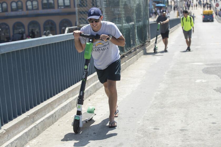 SANTA MONICA, CA-AUGUST 15, 2019: Elliot Stevenson of Auckland, New Zealand grimaces while walking his Lime scooter up a slope towards a designated drop off area after the power was remotely turned off because he rode into an area that is off limits to scooters near the Santa Monica Pier. New and evolving ÒgeofenceÓ agreements between local cities and scooter companies have turned much of the Westside into an invisible obstacle course for riders. To help the perplexed, ÒLime has deployed ÒLime PatrolÓ to parts of Santa Monica. (Mel Melcon/Los Angeles Times)