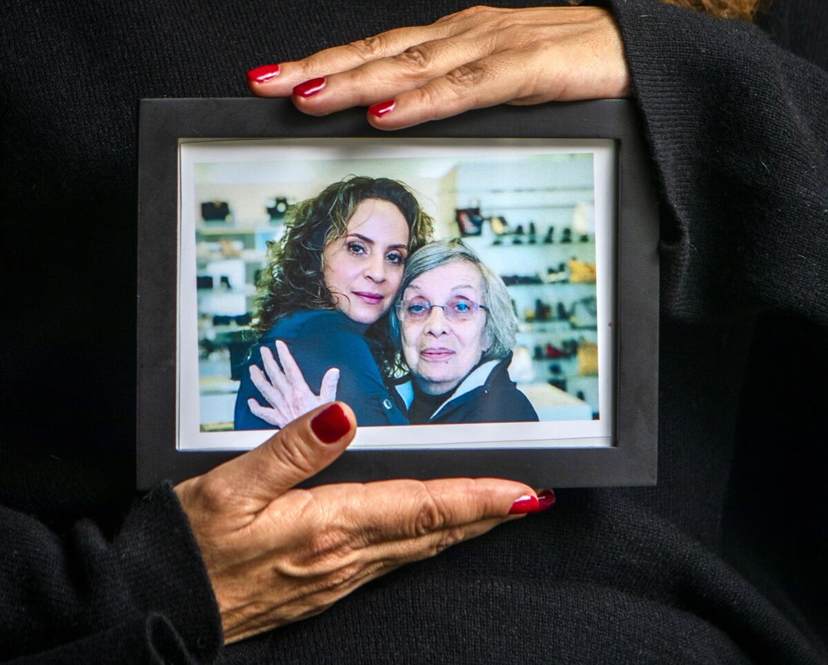 Portrait of Helena Apothaker holding a photograph of her and her mother Catherine in West Hollywood, CA.