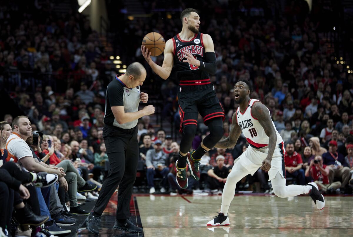 Chicago Bulls guard Zach LaVine, center, saves the ball from going out of bounds in front of Portland Trail Blazers forward Nassir Little, right, during the second half of an NBA basketball game in Portland, Ore., Friday, March 24, 2023. (AP Photo/Craig Mitchelldyer)