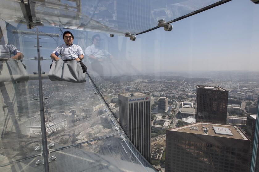 A member of the media takes a 4-second ride on the SkySlide, 1,000 feet above downtown Los Angeles at the U.S. Bank Tower. The slide is part of OUE Skyspace LA, the tallest open-air observation deck in California, offering visitors a 360-degree view of the city.