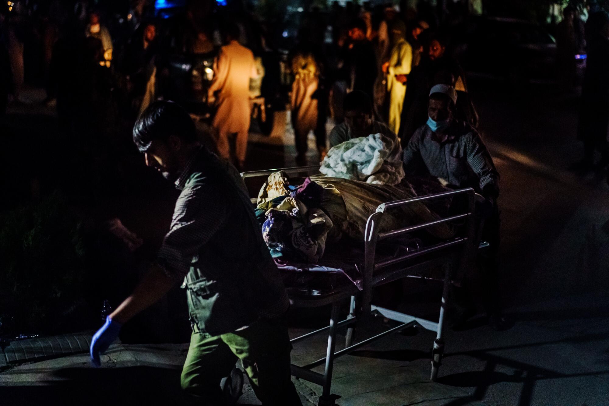 Hospital staff rolls a patient on a gurney in the darkness