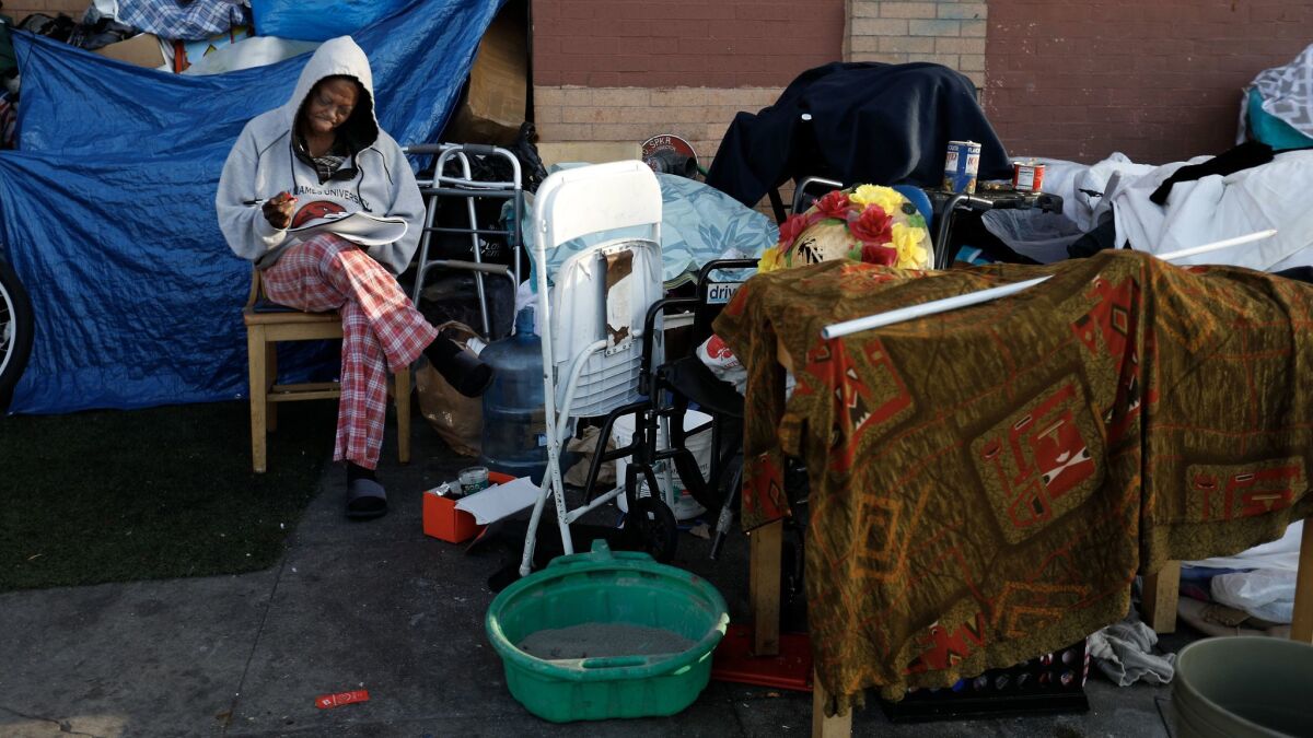 A woman writes in her journal on 5th street in the skid row area of Los Angeles.