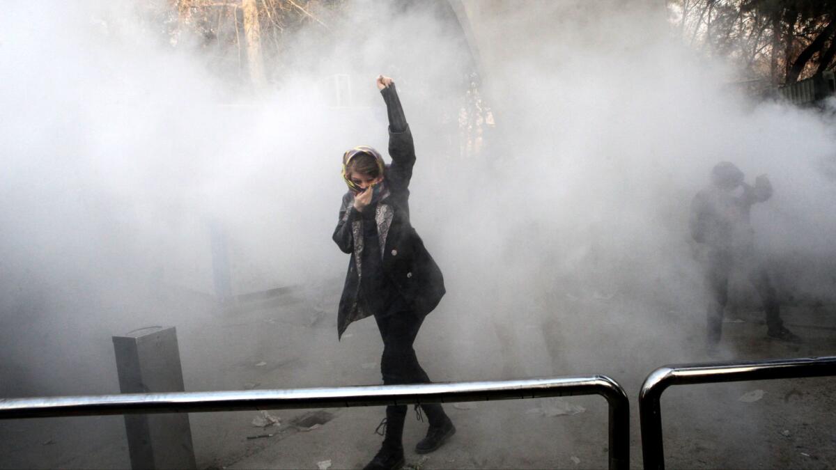 An Iranian woman raises her fist amid the smoke of tear gas at the University of Tehran during a protest on Dec. 30.