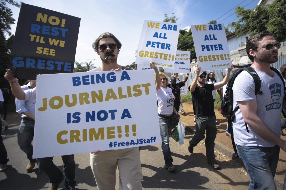 Foreign correspondents hold placards denouncing the imprisonment of Al Jazeera journalists, including Australian Peter Greste, in Egypt as they walk toward the Egyptian Embassy in Nairobi, Kenya.