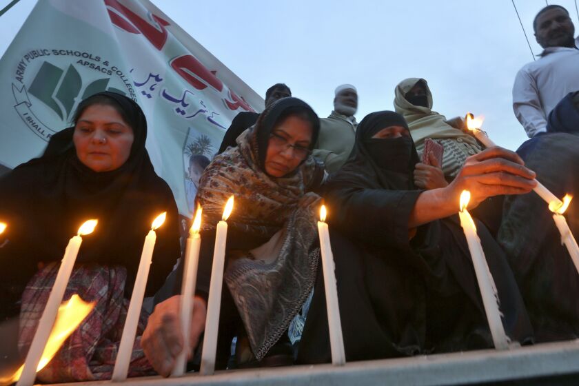 Women light candles during a prayer ceremony for victims of Monday's suicide bombing inside a mosque, in Peshawar, Pakistan, Wednesday, Feb. 1, 2023. (AP Photo/Muhammad Sajjad)