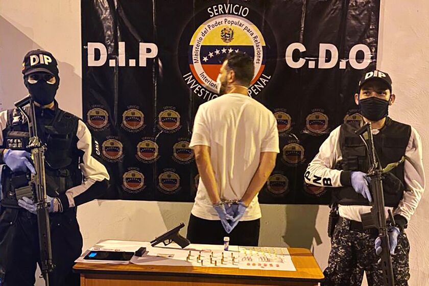 In this March 31, 2020, photo, Venezuelan police officers present a suspect arrested at a multiday party in Caracas, Venezuela, that violated Nicolas Maduro’s order on large gatherings during the coronavirus pandemic. (Courtesy of Venezuelan Chief Prosecutor’s Office via AP)