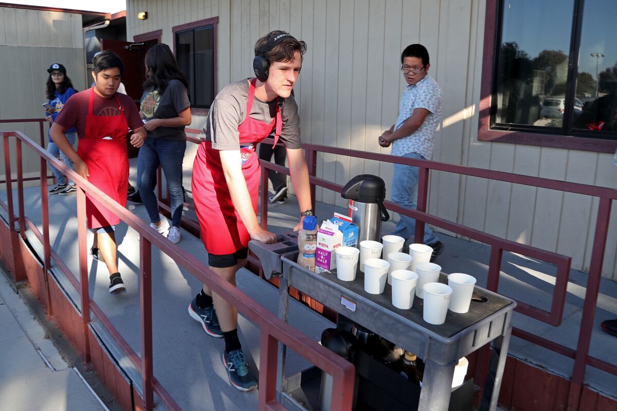 IDEAs students Alex Wright, center, and Hong Lai head out to deliver coffee orders to classrooms Friday.