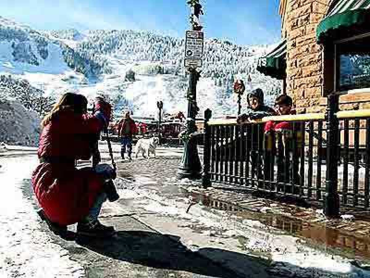 A mother photographs her sons with Aspen Mountain in the background.